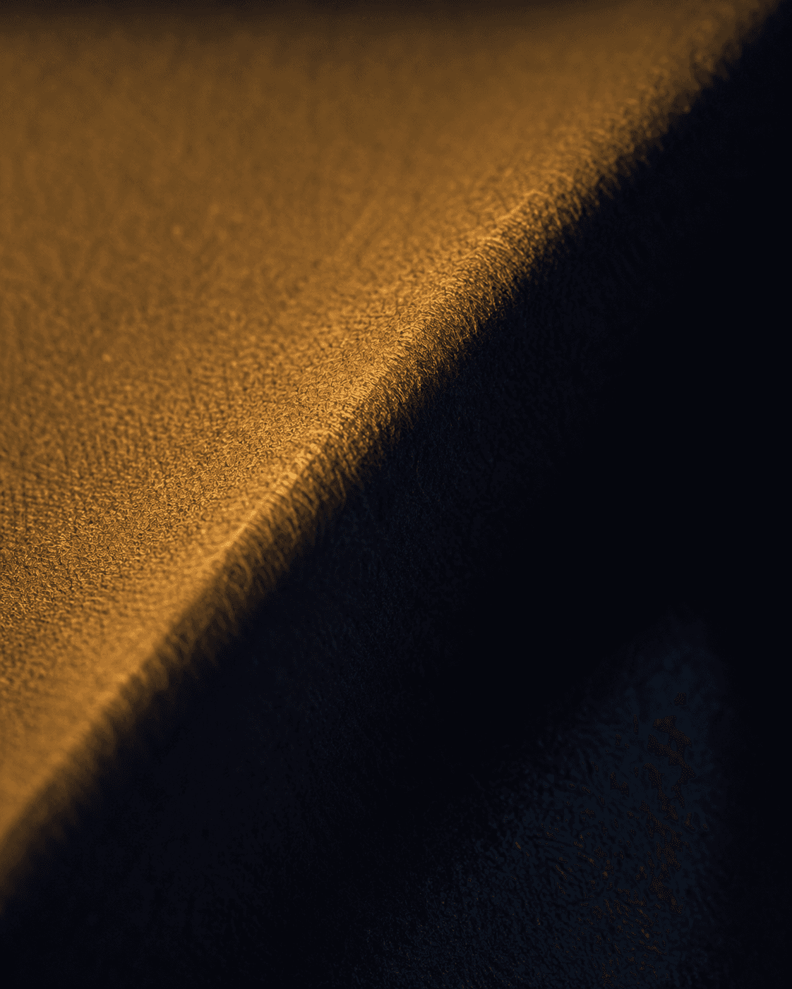A single diagonal fold in heavy matte fabric, one face lit and one in shadow.